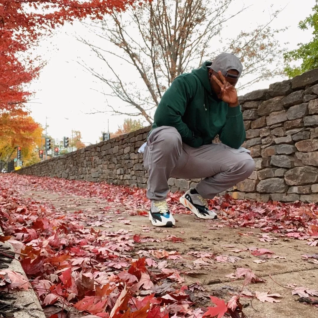 Mon Moore crouched on a path covered in red autumn leaves