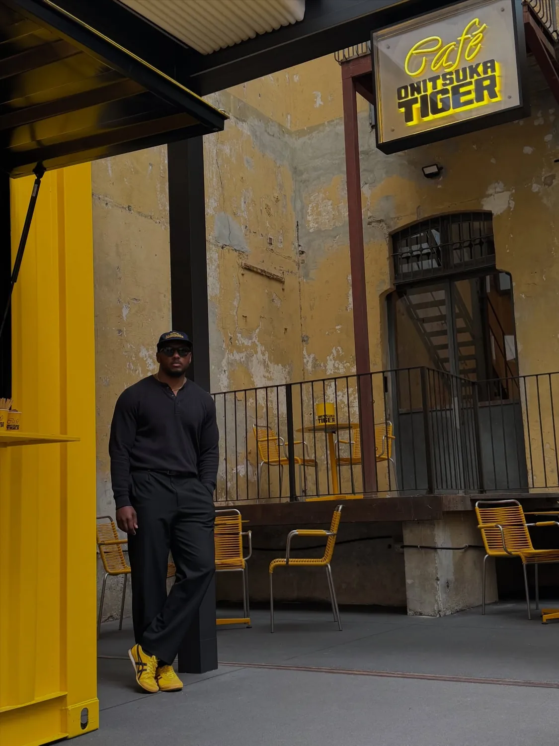 Mon Moore in black against a gold-lit café wall